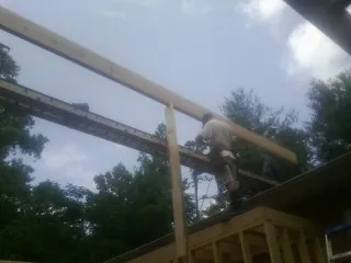 Carpenter setting a ridge beam over a new addition frame — Ice Dam Removal by Roofing Brothers in Mexia