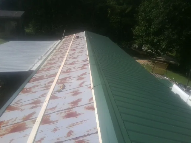 Old rusted panels beside newly installed green metal roofing — Wind Damage Roof Repair by Roofing Brothers in Mexia