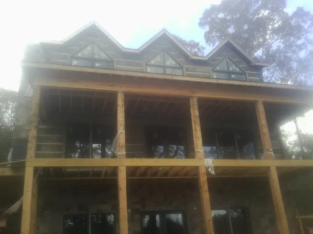 Dormers and porch framing on a large log home under construction — Roof Coating work by our crew in Mexia