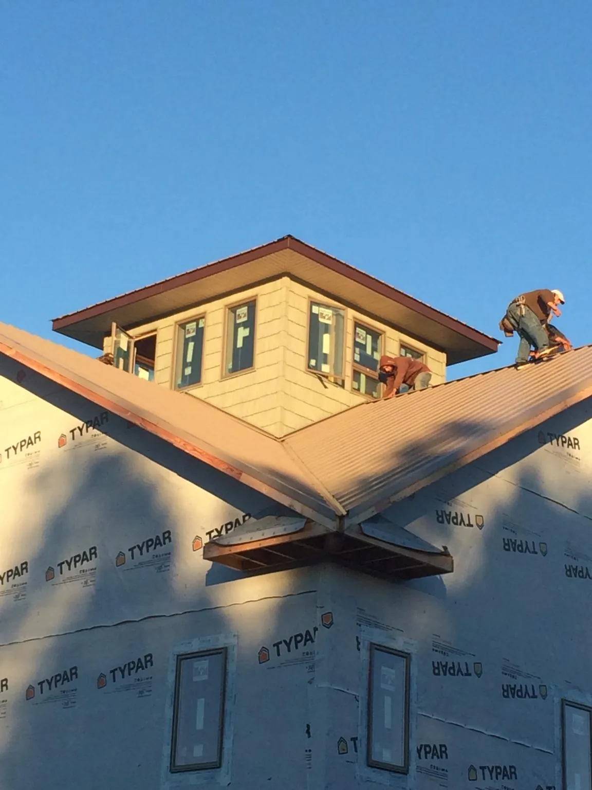 Roofers working around a rooftop cupola on a new metal roof at sunset — Roof Waterproofing in Mexia by Roofing Brothers